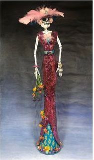 A skeleton figurine wearing a 1920's style dress holding a bouquet of flowers. 