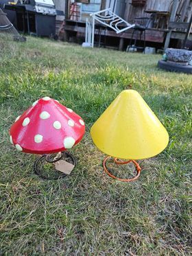 Two mushroom shaped lamps are sitting on top of a lush green field.