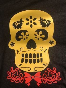 A black shirt with a gold sugar skull on it