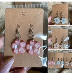 A person is holding a card with a pair of earrings on it.