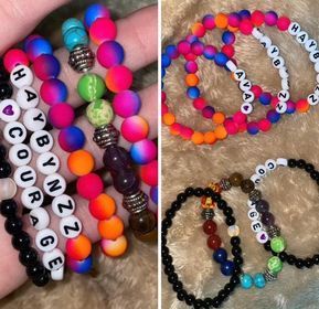 A person is holding a bunch of colorful bracelets with letters on them