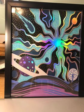 A framed painting of a planet in space with a rainbow coming out of it.