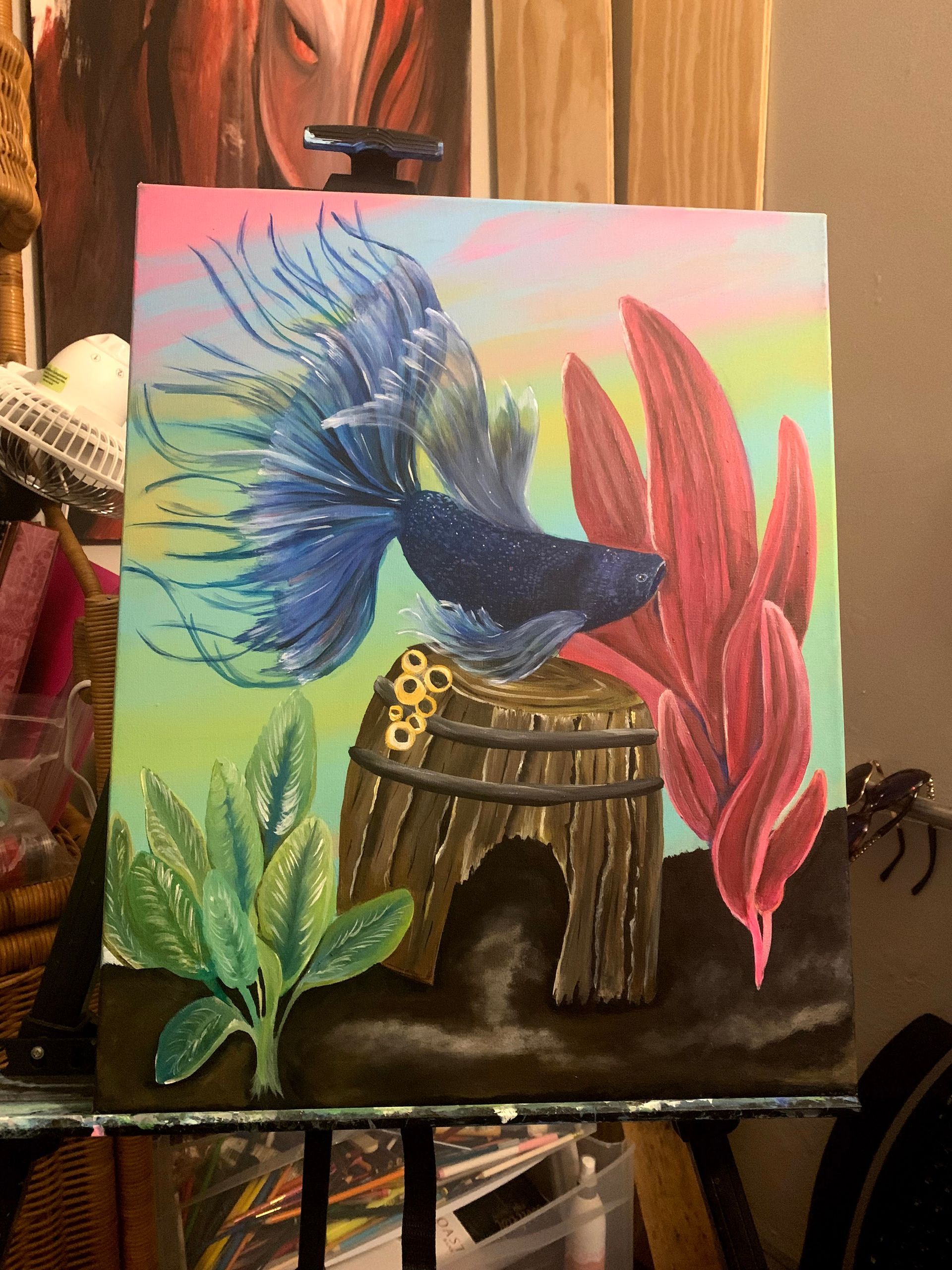 A painting of a fish and plants on an easel.