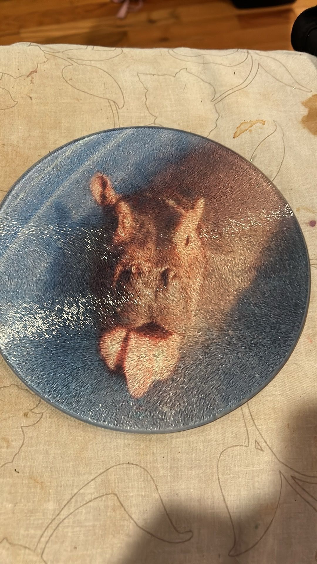 A blue plate with a picture of a hippo on it is sitting on a table.