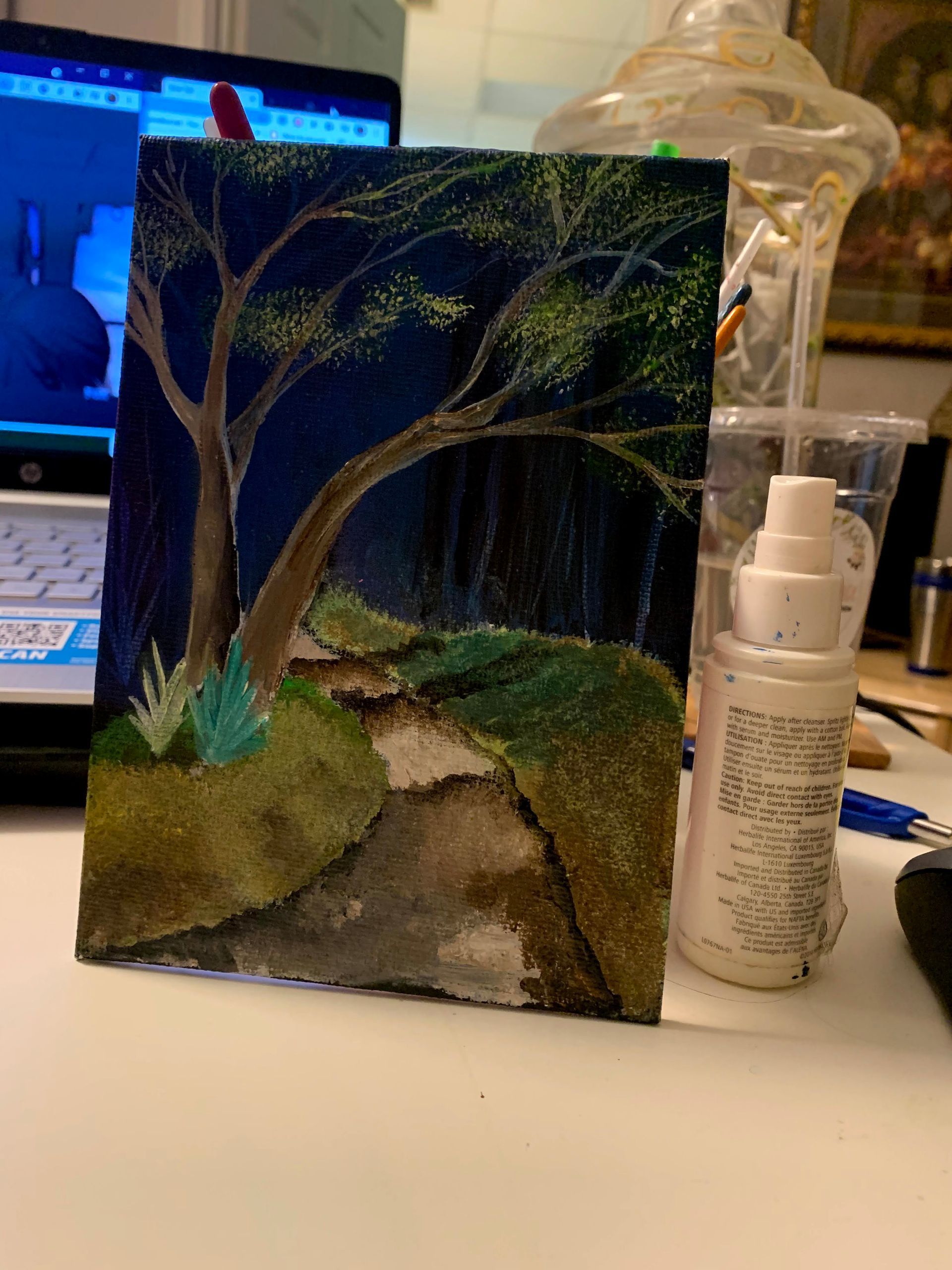 A painting is sitting on a table next to a spray bottle