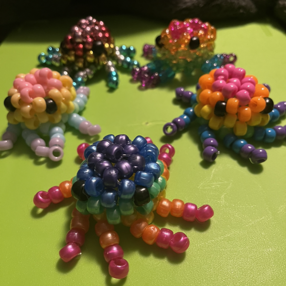 A group of colorful octopi made from beads are sitting on a green surface