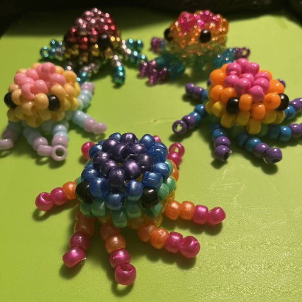 A group of beaded octopus are sitting on a green surface.