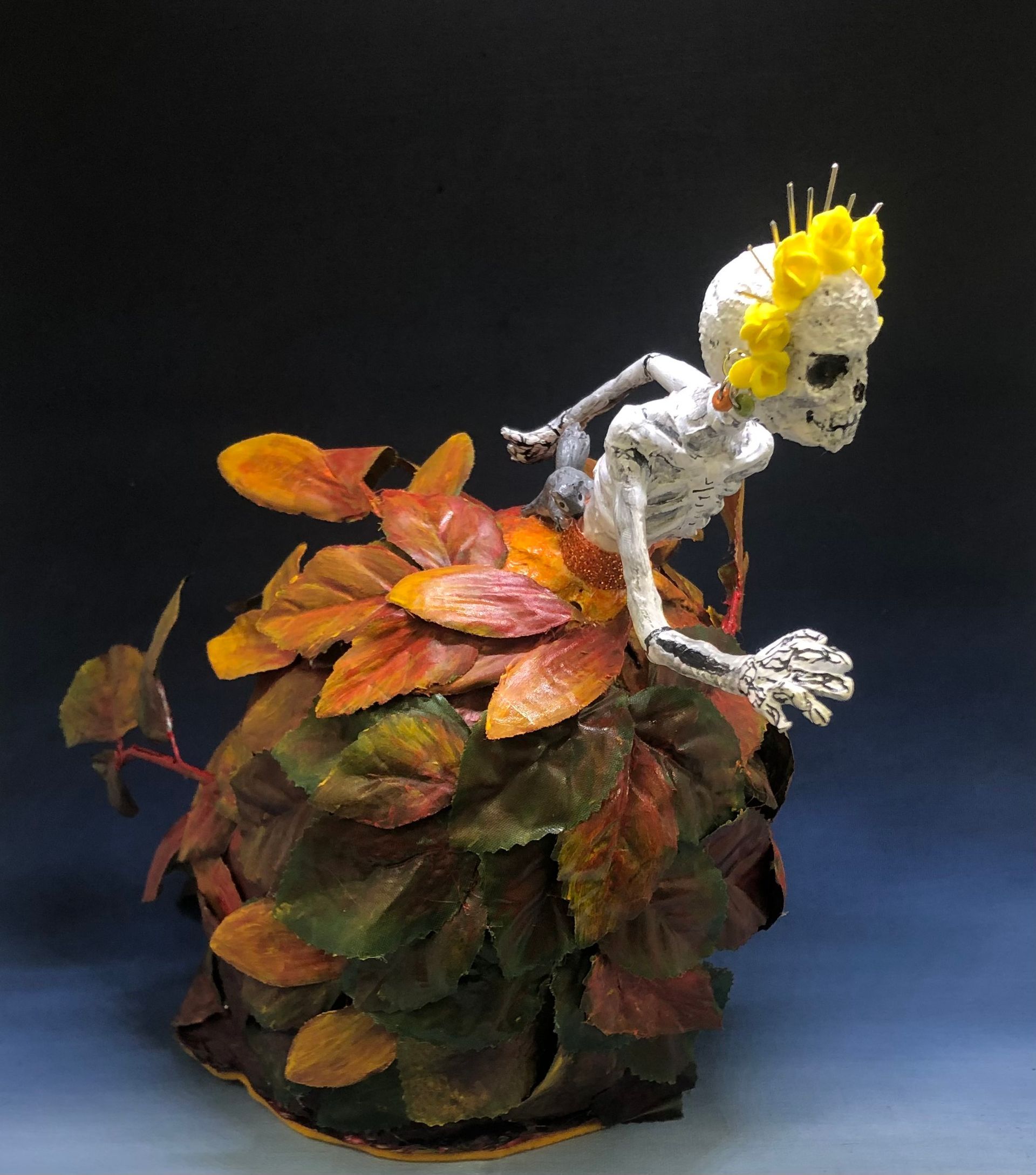 A skeleton is sitting on a pile of leaves