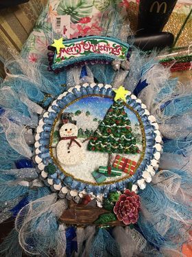 A christmas wreath with a snowman and a christmas tree on it.