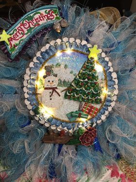A christmas wreath with a snowman and a christmas tree on it.