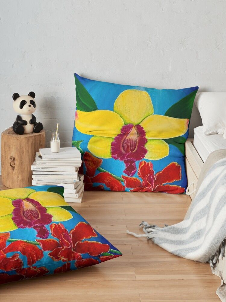 A pillow with a yellow flower on it is sitting on a wooden floor next to a bed.