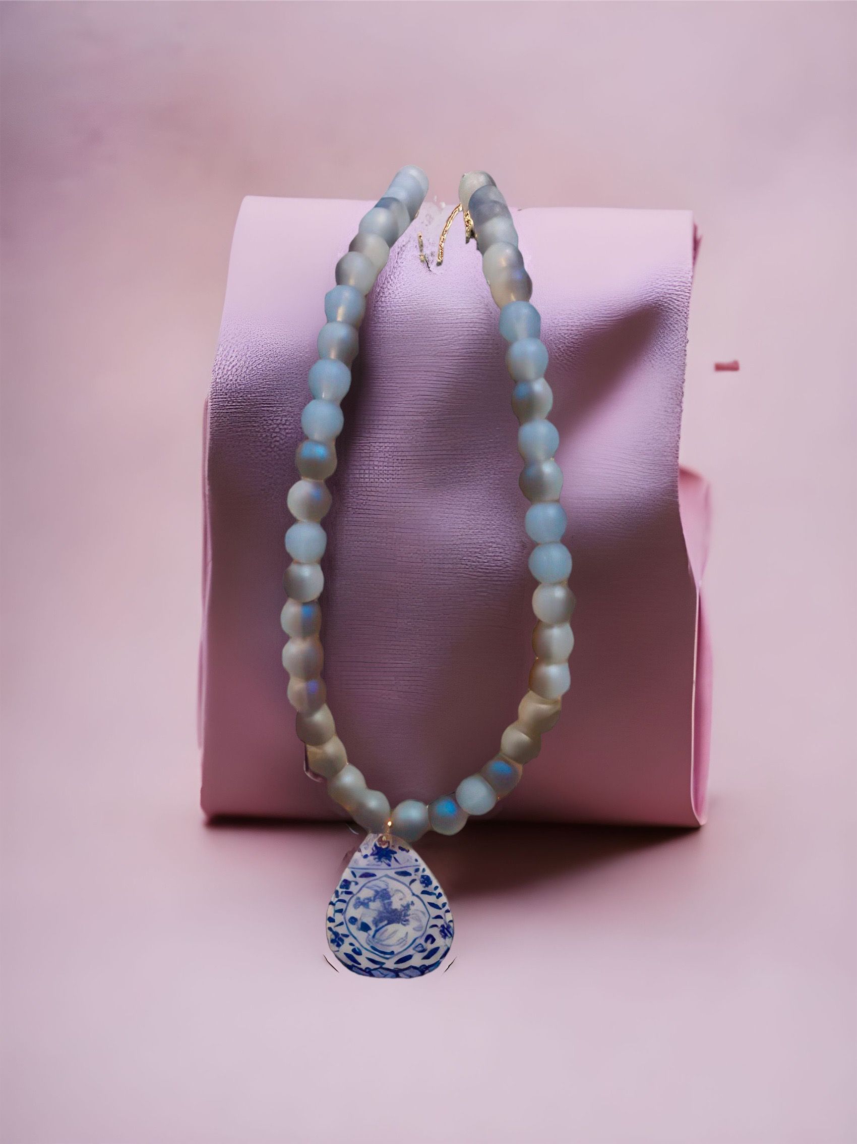 A necklace is sitting on top of a pink piece of paper.