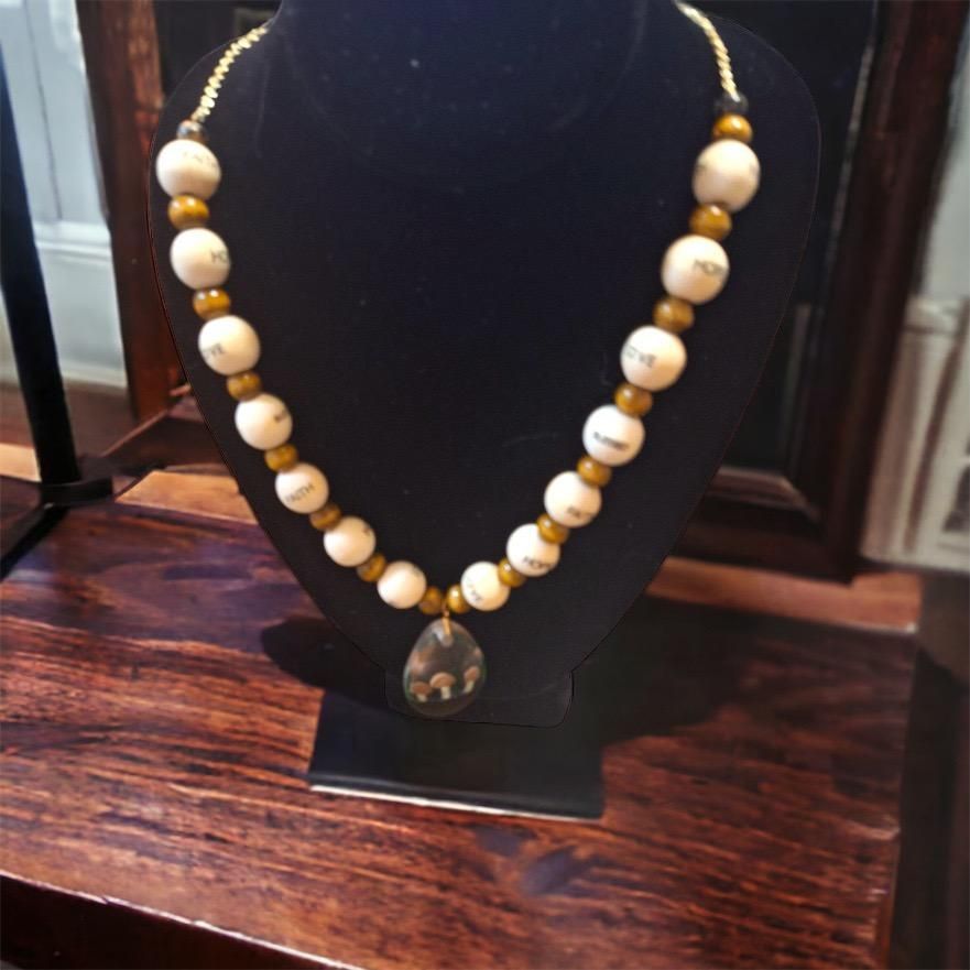 A necklace with white and gold beads is on a mannequin