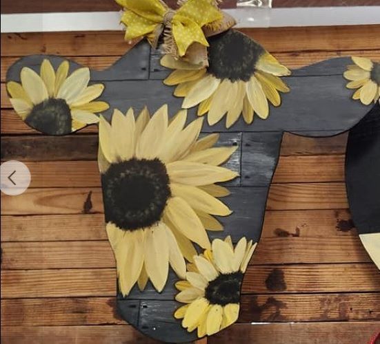 A wooden cow head with sunflowers on it