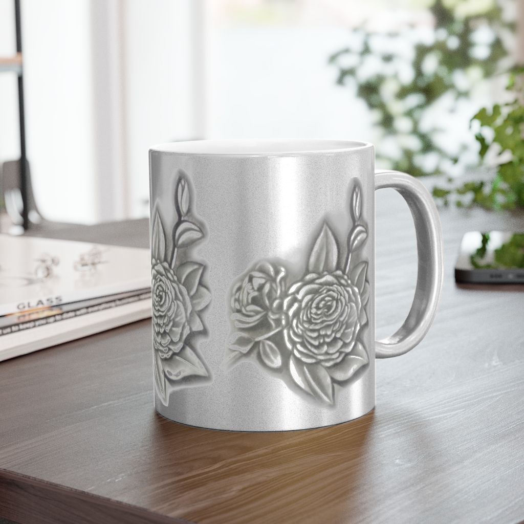 A silver mug with flowers on it is sitting on a wooden table.