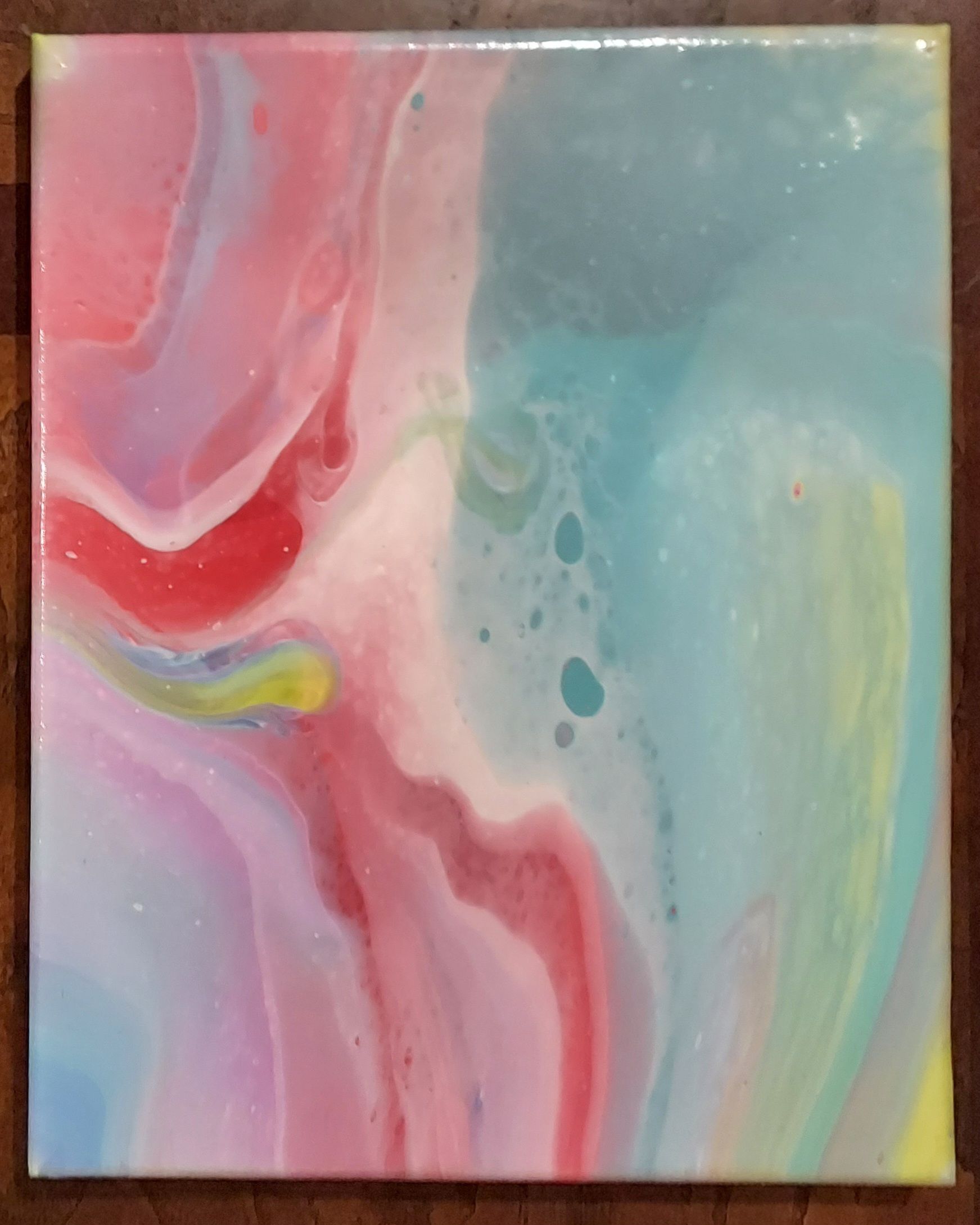 A colorful painting is sitting on a wooden table.