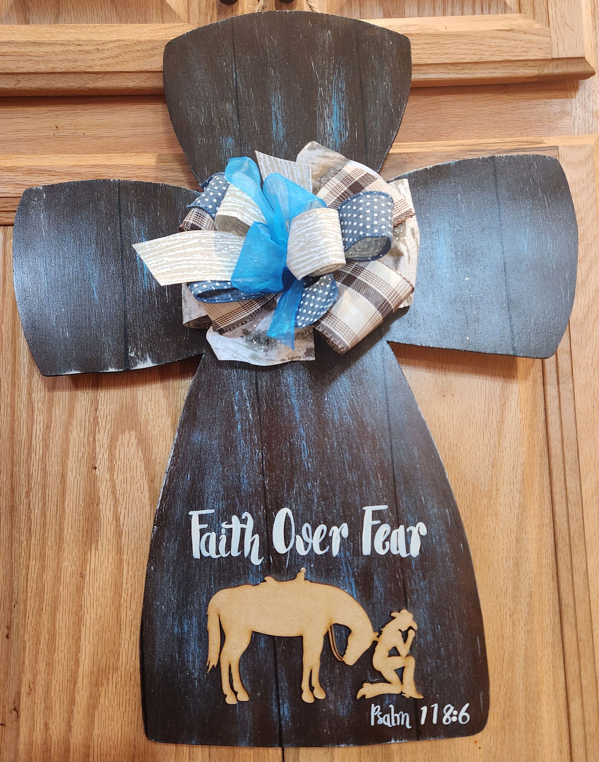 A wooden cross with a horse on it is hanging on a wooden door.