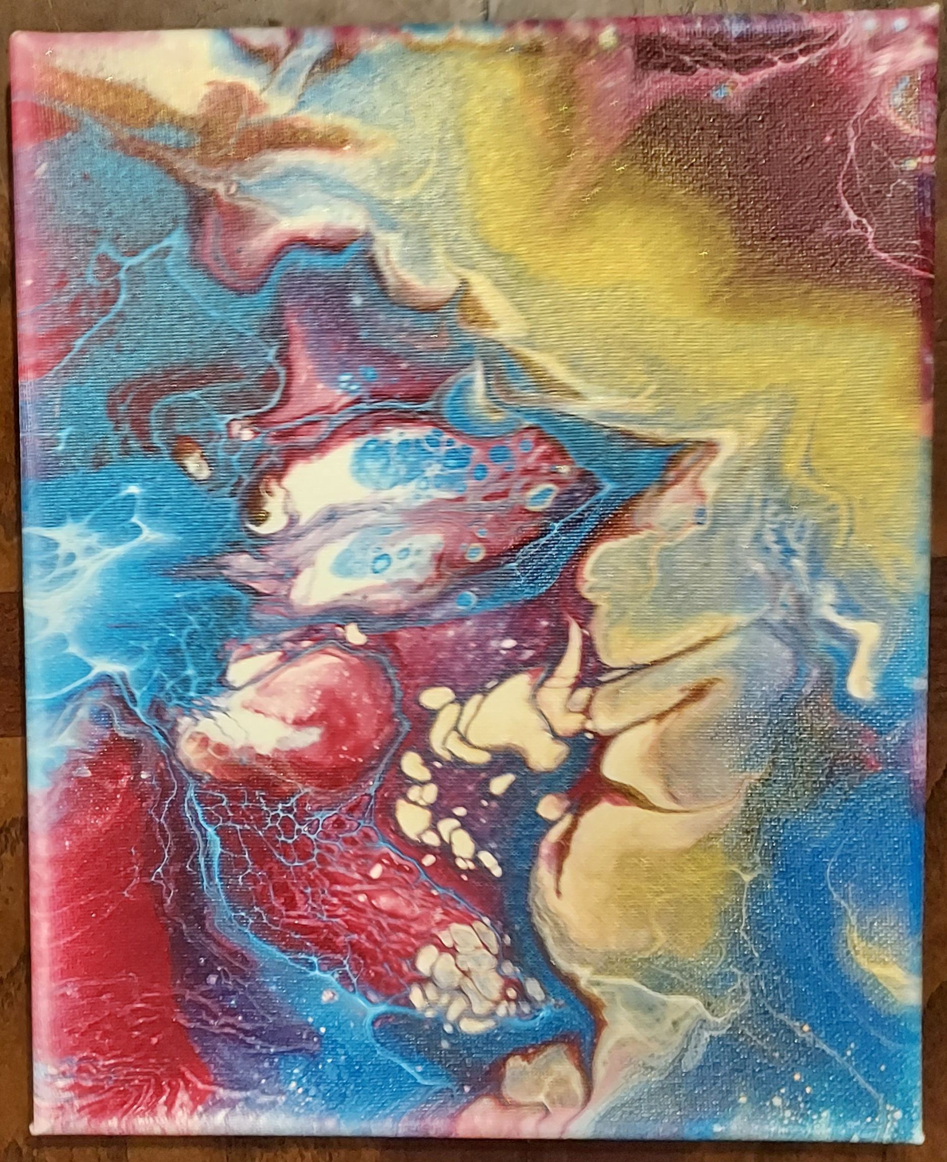 A colorful painting is sitting on a wooden table.