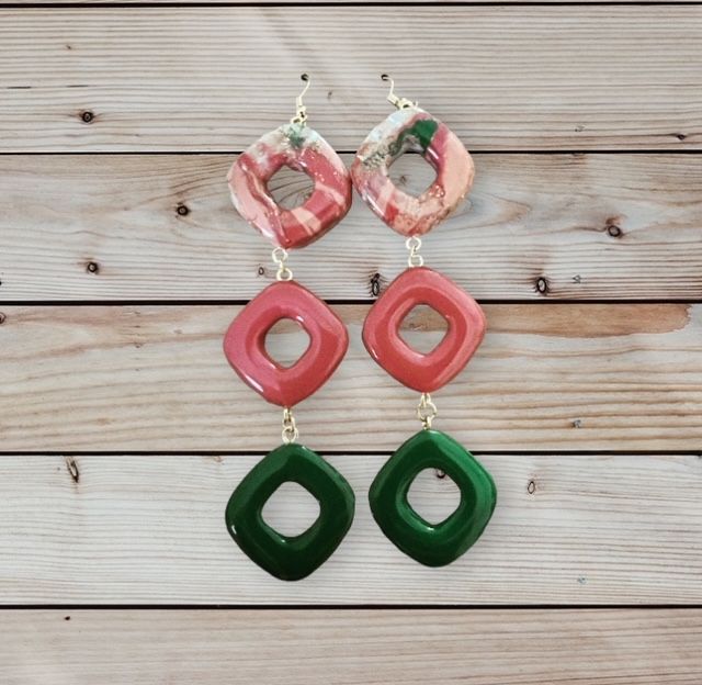 A pair of red and green earrings on a wooden surface