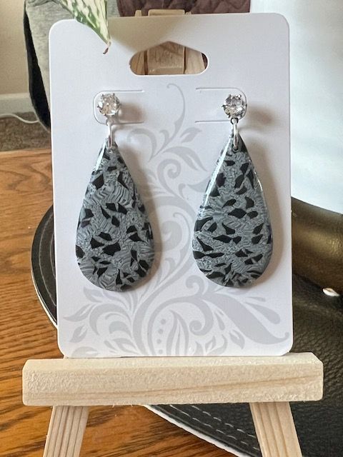 A pair of earrings are sitting on a card on a wooden easel.