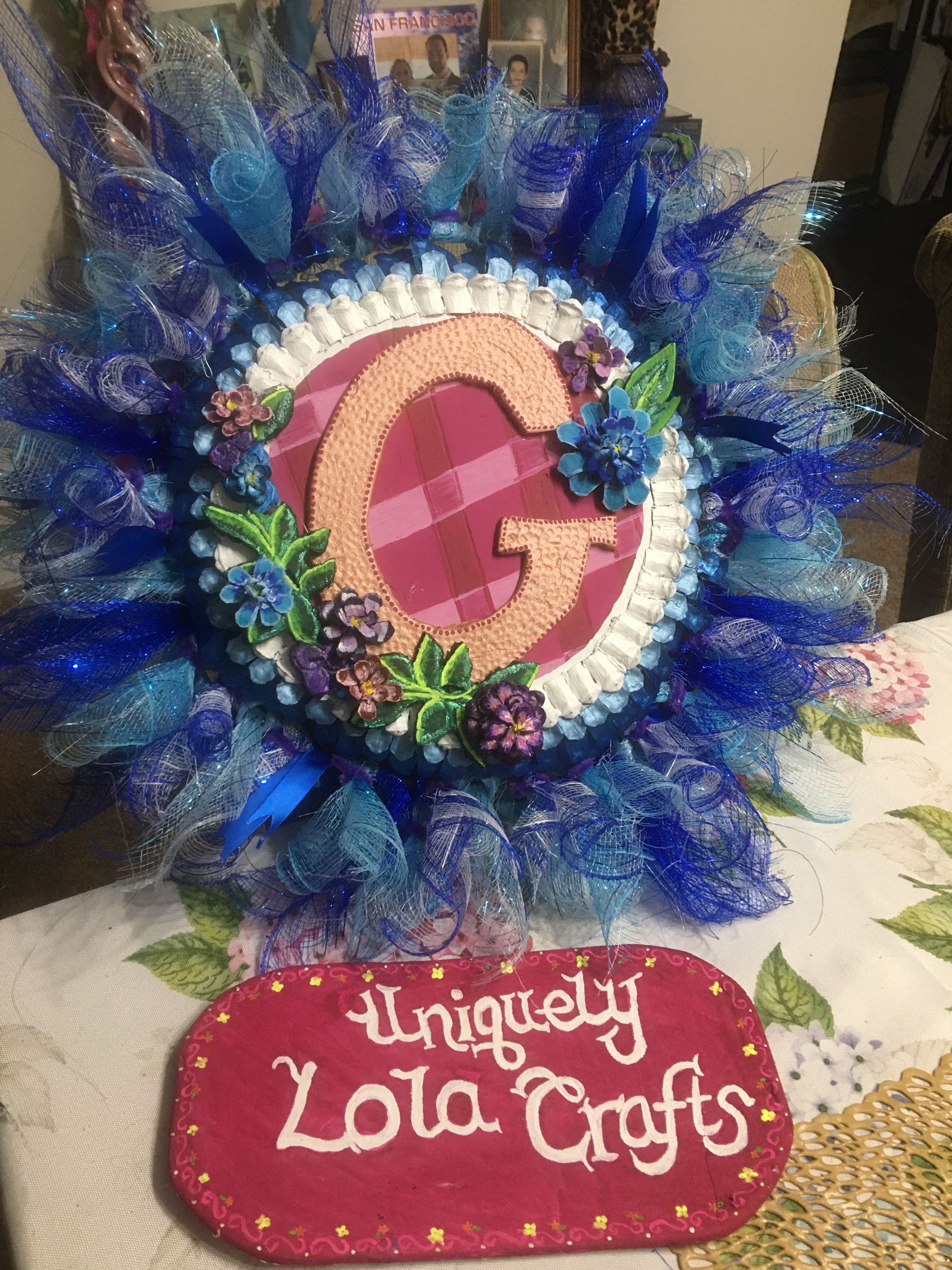 A wreath with a letter g on it is sitting on a table.
