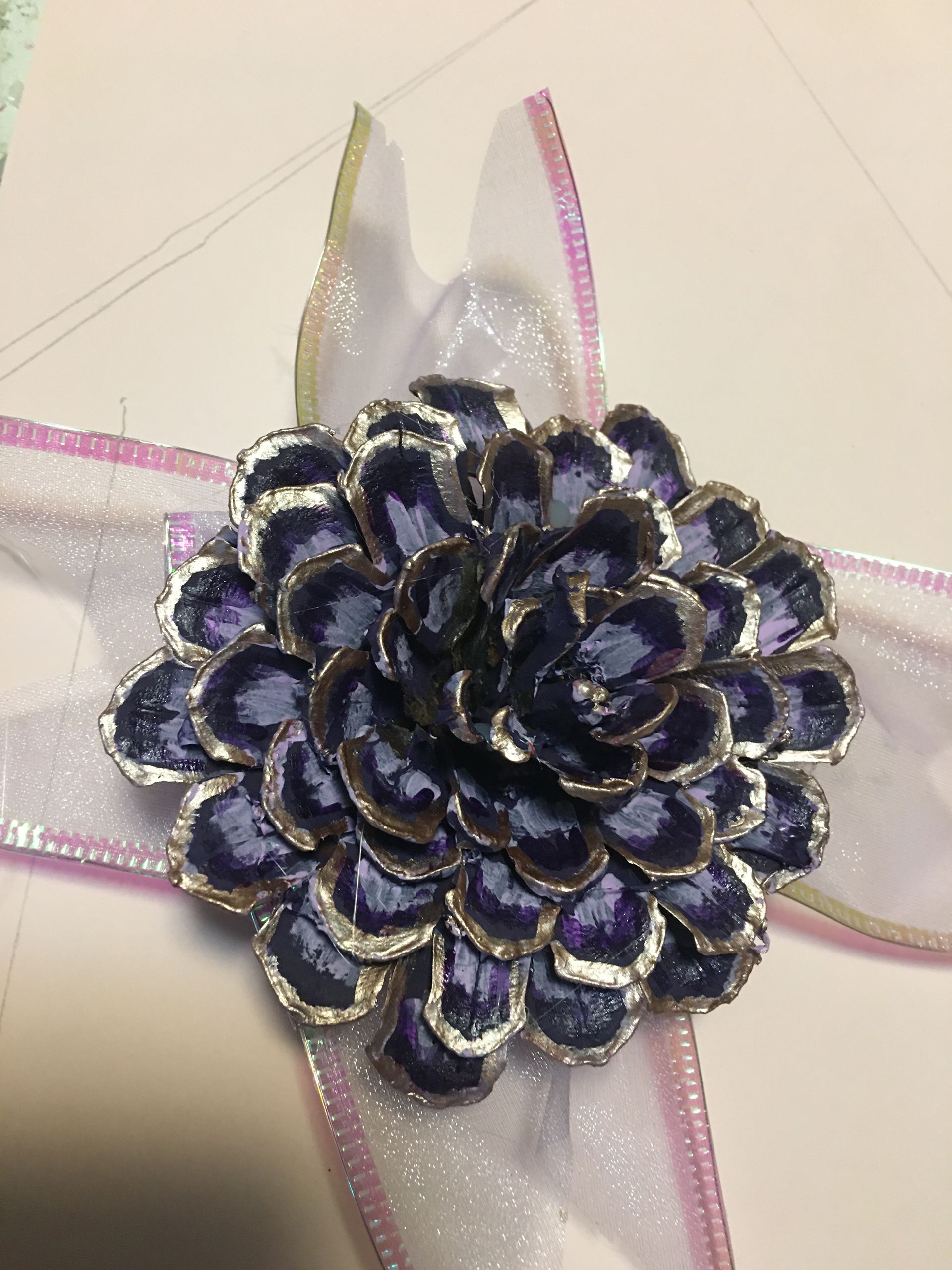 A close up of a purple flower on a white ribbon