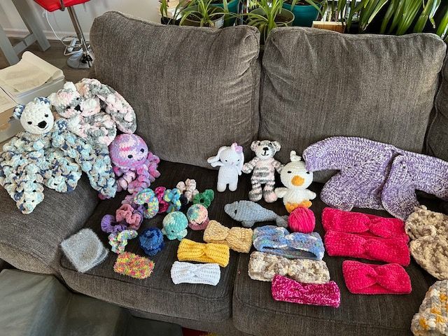 A couch filled with lots of stuffed animals and knitted items.