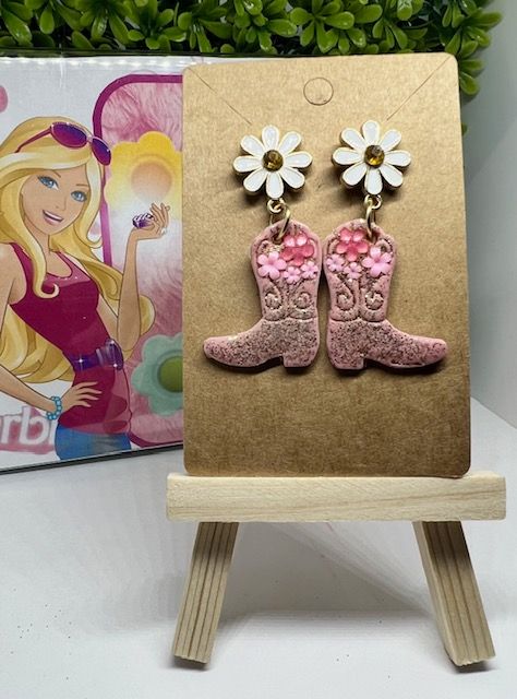 A pair of pink cowboy boots with white daisies on them