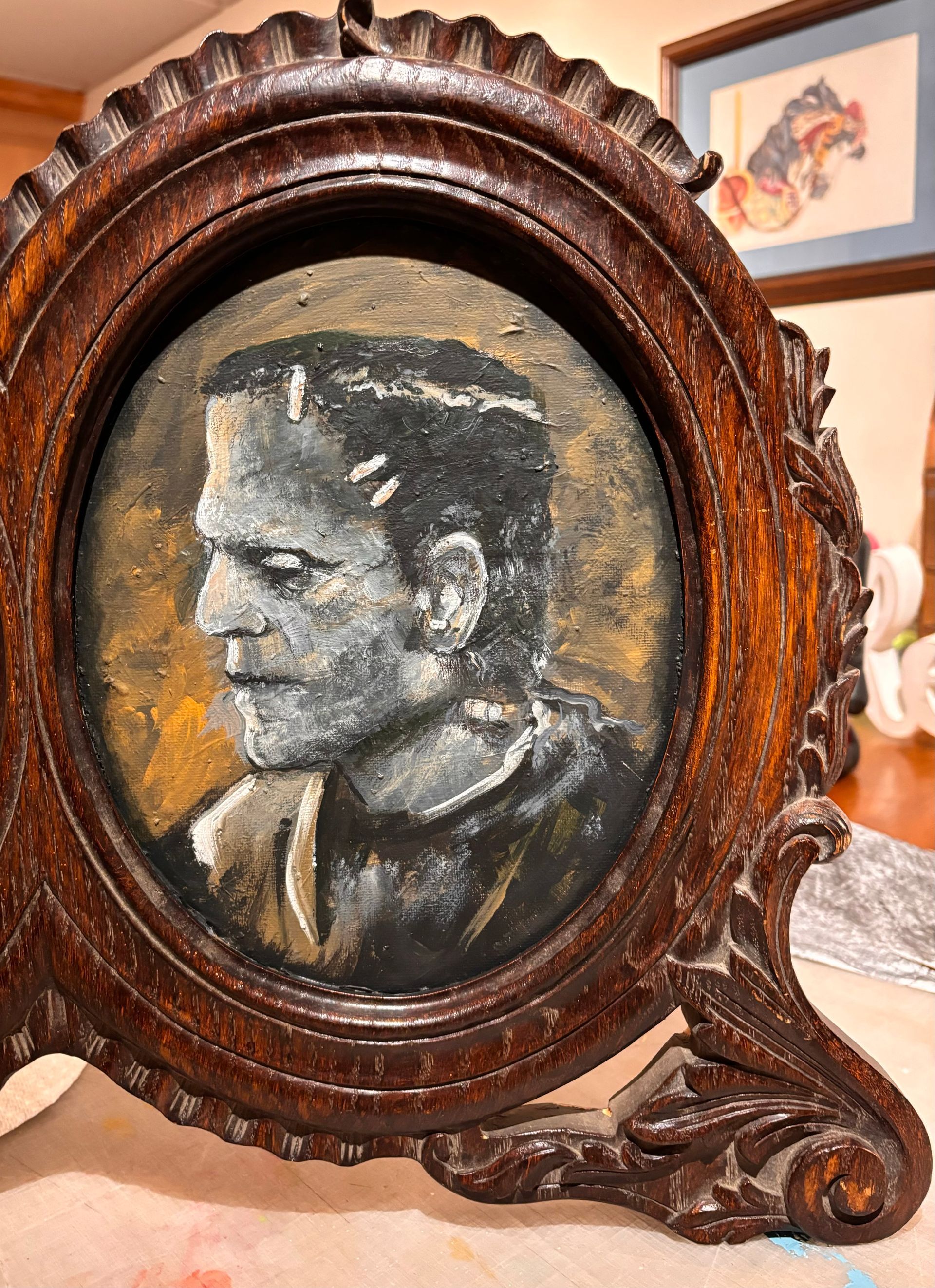 A painting of frankenstein is in a wooden frame.