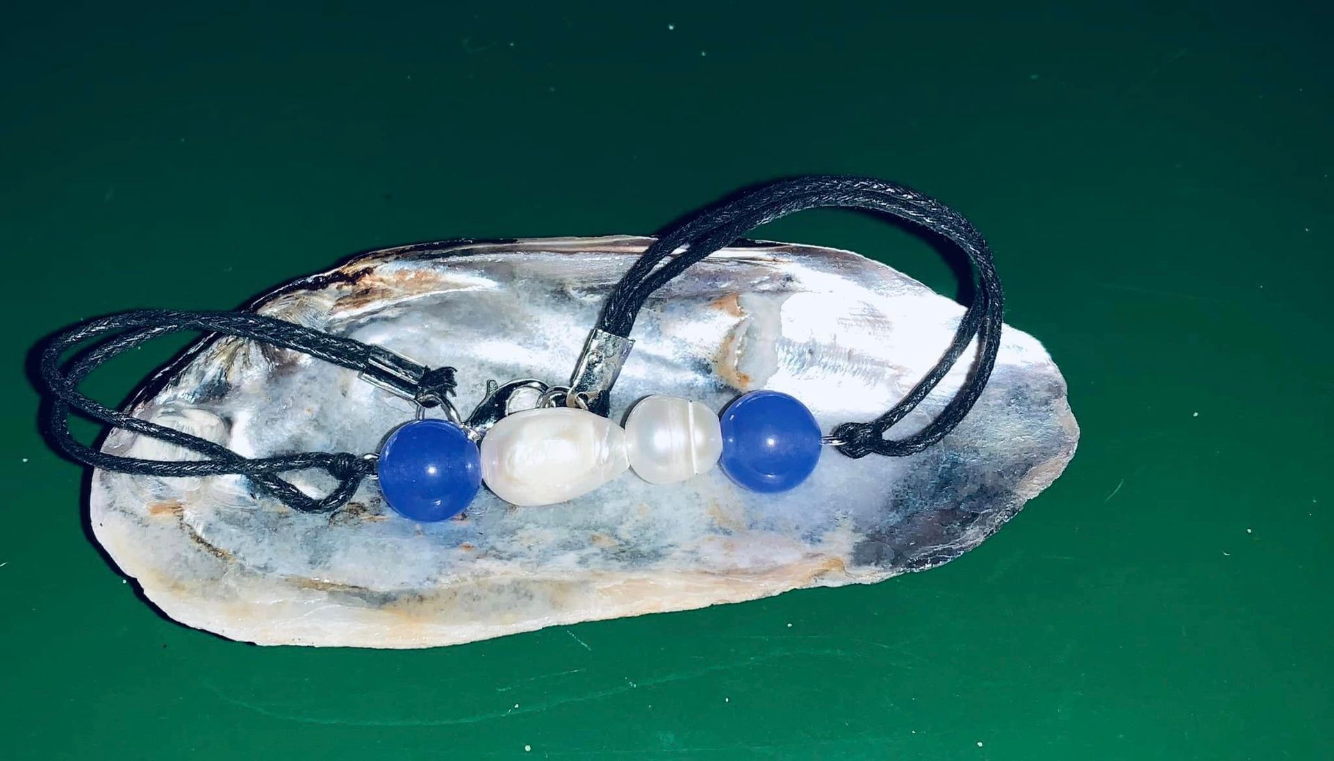A bracelet is sitting on top of an oyster shell.