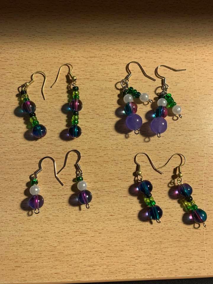 Four pairs of earrings are sitting on a wooden table.