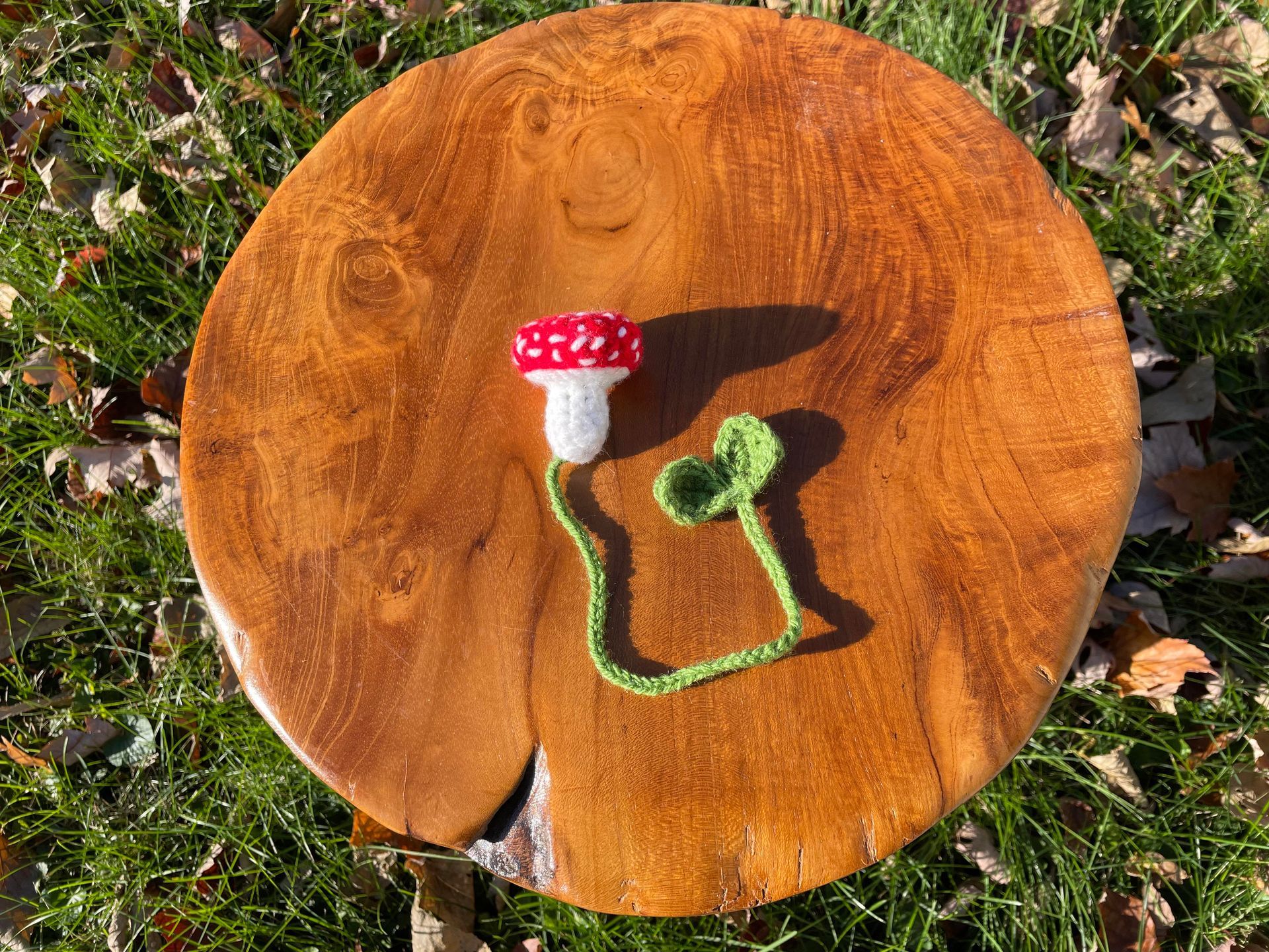 A crocheted mushroom is sitting on top of a wooden cutting board.