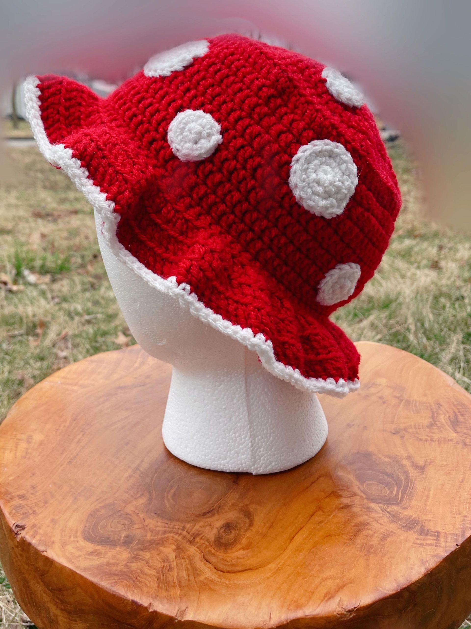 A crocheted mushroom hat is sitting on top of a wooden block.