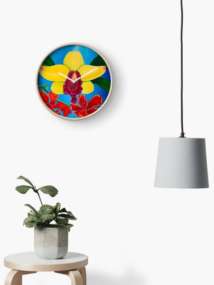 A clock with a colorful on a wall next to a plant and a lamp