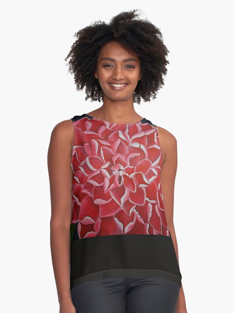 A woman is wearing a sleeveless top with a pattern of red flowers on it.