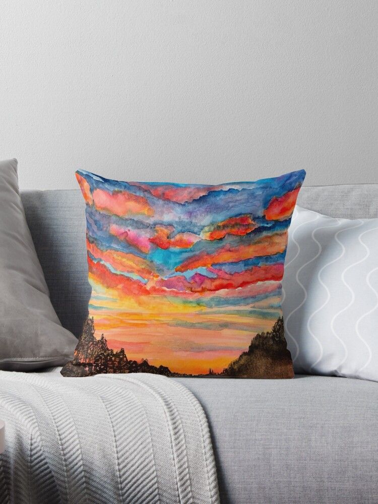 A pillow is sitting on a couch next to a blanket.