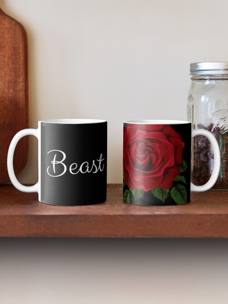 Two coffee mugs with the word beast on them are sitting on a wooden shelf.