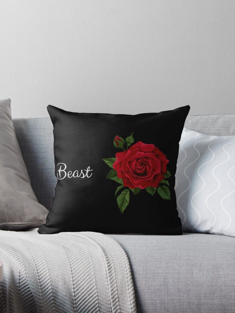 A black pillow with a red rose on it is sitting on a couch.