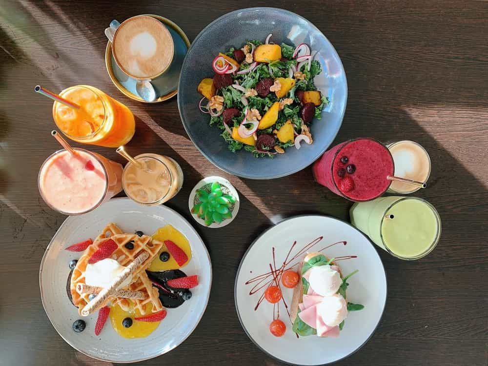Table Topped With Plates Of Food and Drinks — Café and Restaurant in Cannonvale, QLD