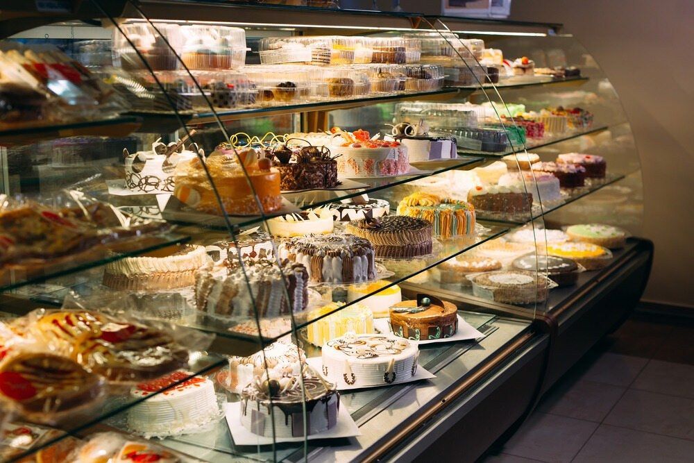 A Display Case Filled With Lots Of Cakes In A Bakery — Café and Restaurant in Whitsundays, QLD