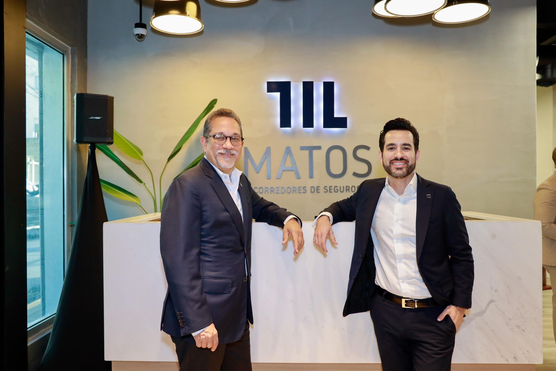 two men are standing next to each other in front of a sign that says matos .