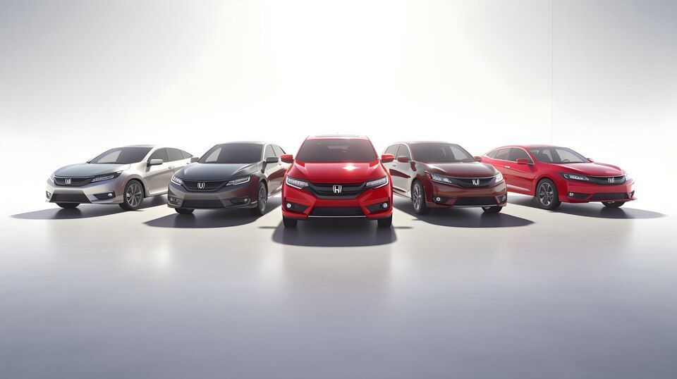 Uma fila de cinco carros Honda de cores variadas, estacionados em um estúdio fotográfico contra um fundo branco brilhante.