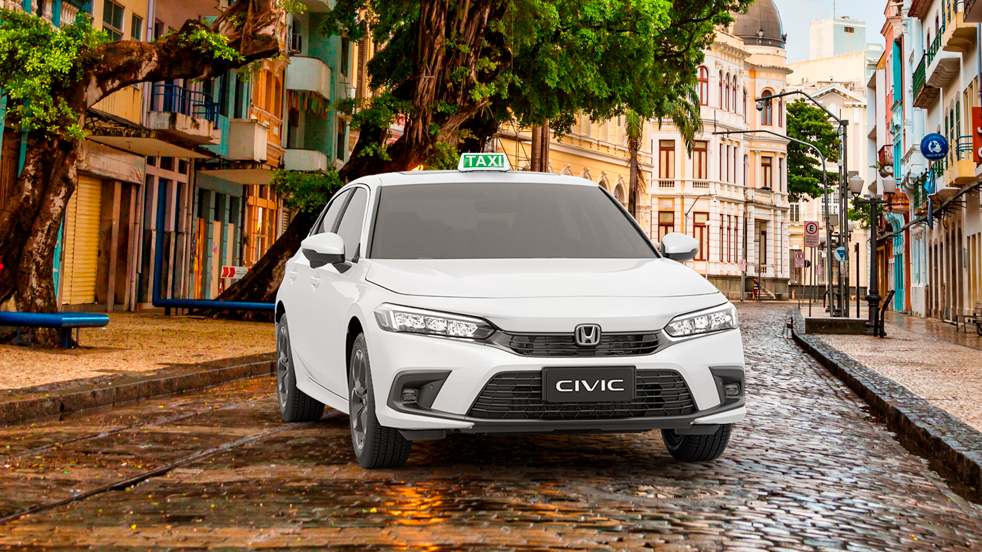 Um táxi Honda Civic branco estacionado em uma rua de paralelepípedos molhada, ladeada por prédios históricos coloridos.