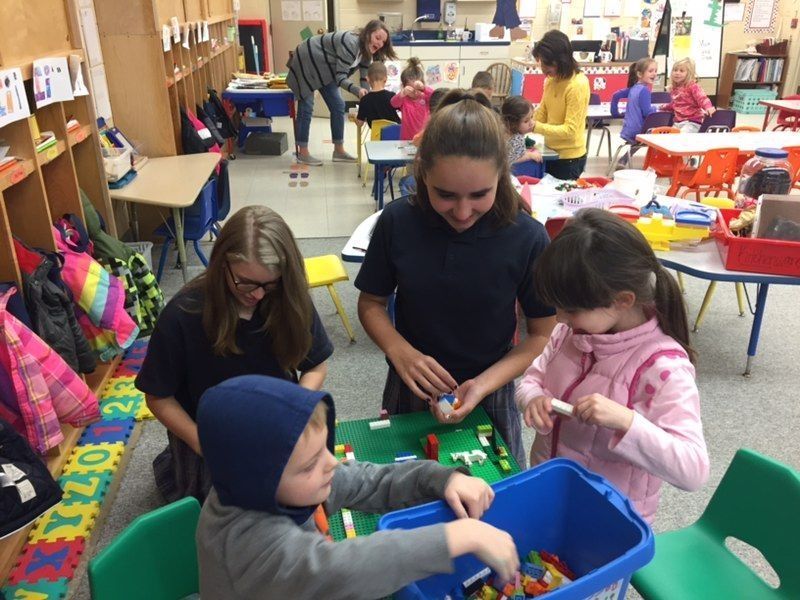 A group of children are playing with lego blocks in a classroom