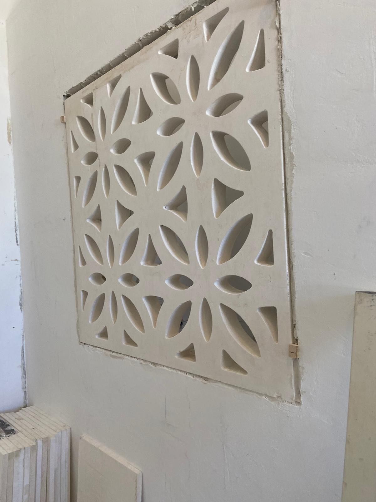 Un muro bianco con un motivo geometrico inciso.