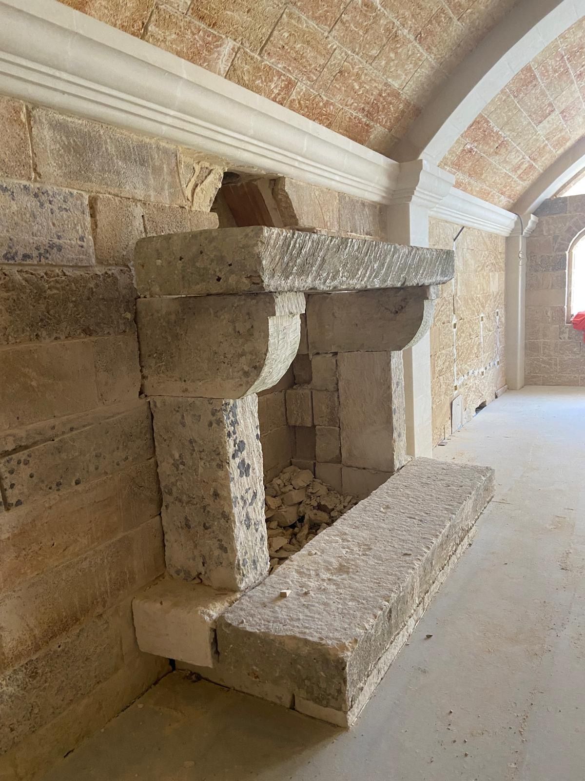 Un camino in pietra si trova in una stanza accanto a un muro di mattoni.
