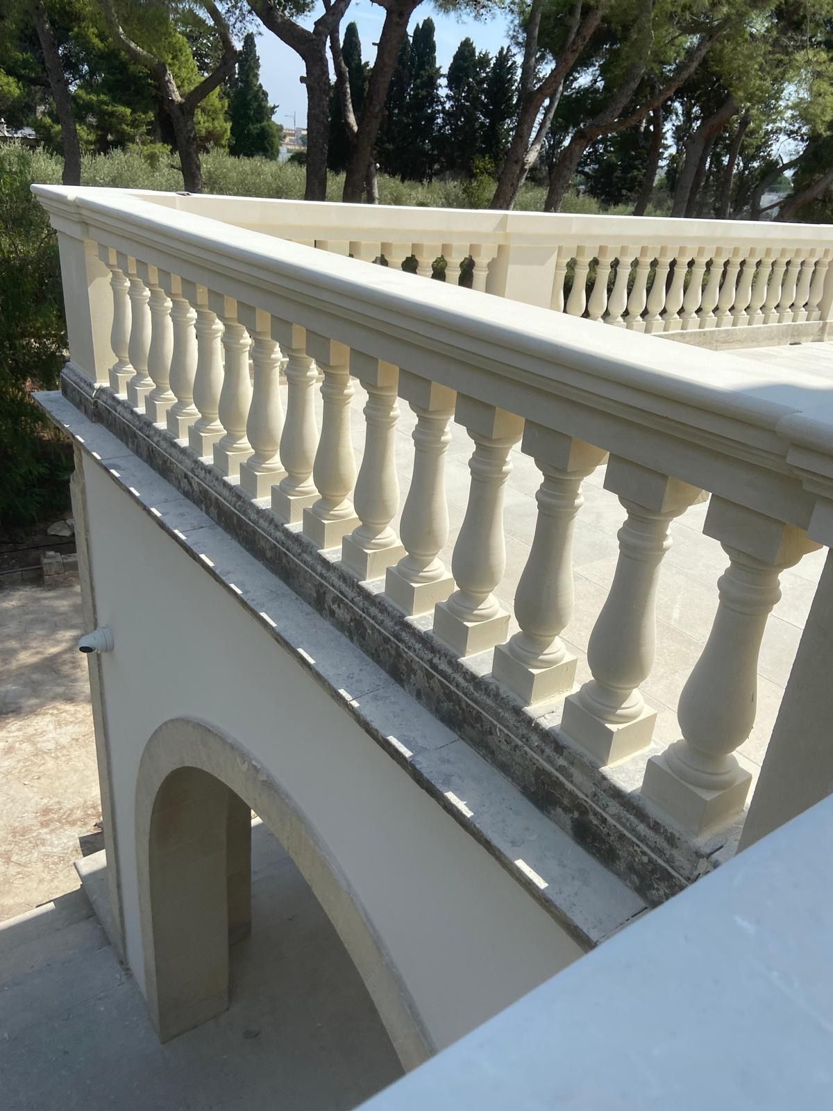 Un balcone con una ringhiera bianca e alberi sullo sfondo