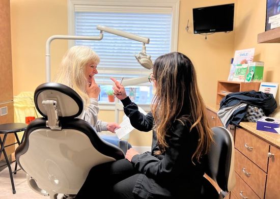 Dentist pointing to paperwork while speaking to patient in a dental office.