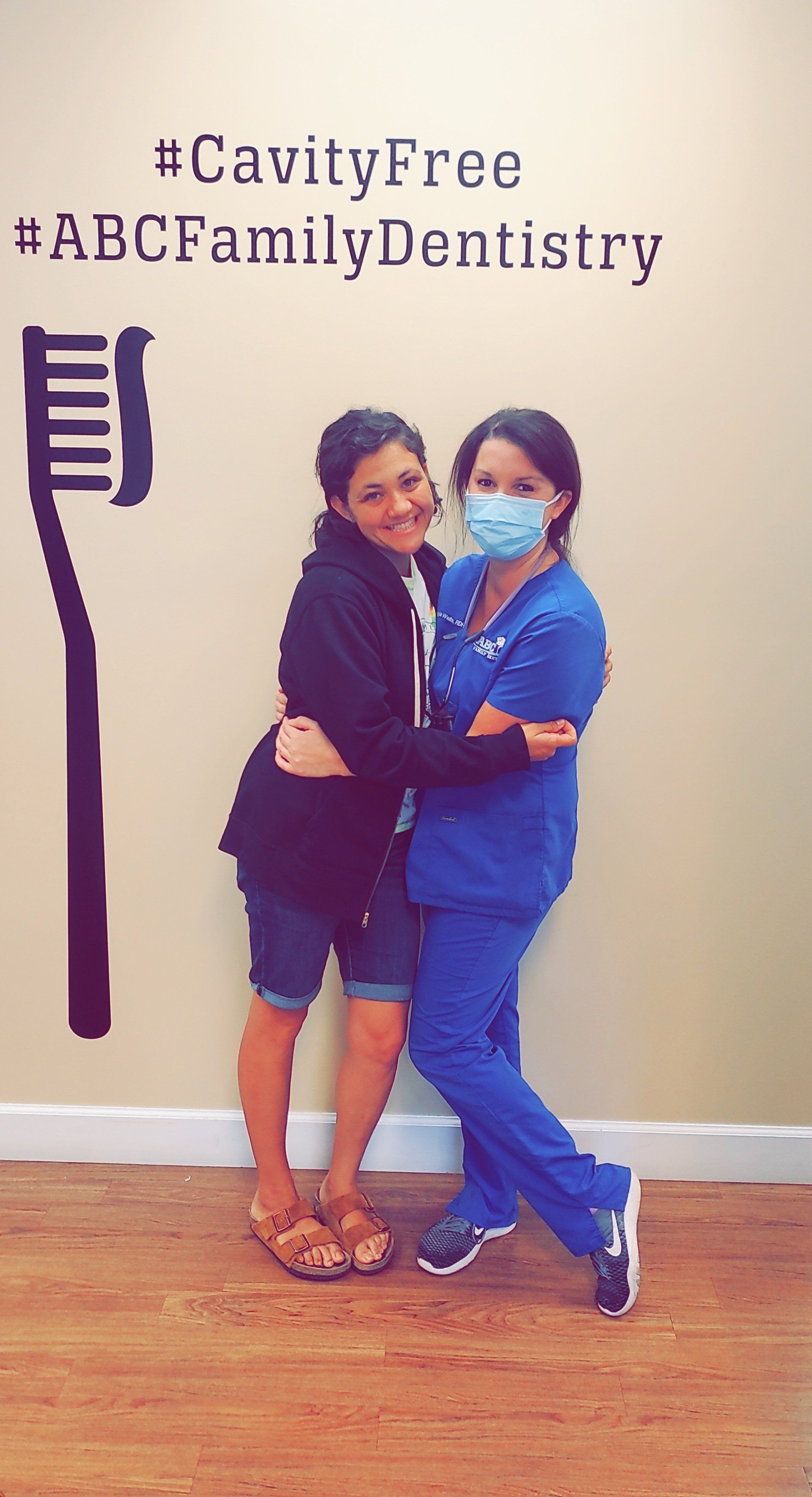 Woman hugs dentist in blue scrubs at ABC Family Dentistry.