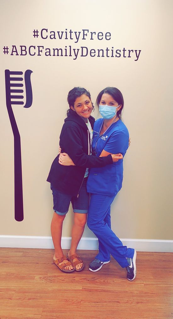 Woman hugs dentist in blue scrubs at ABC Family Dentistry.